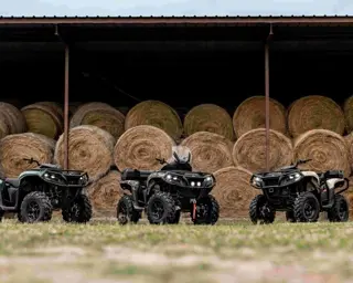 Tre fyrhjulingar framför höbalar